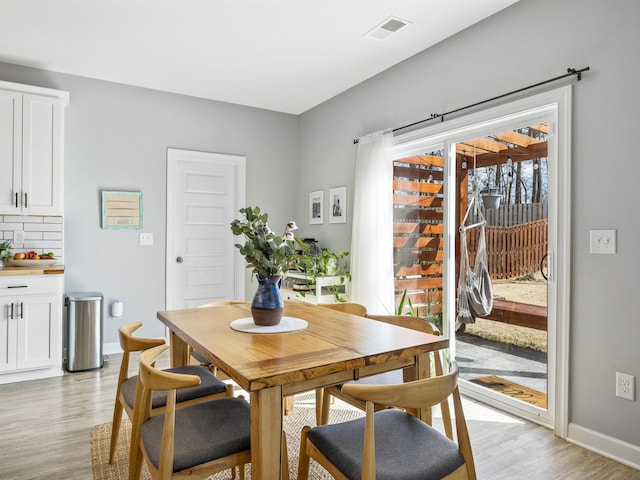 dining area with light wood-style floors, visible vents, and baseboards