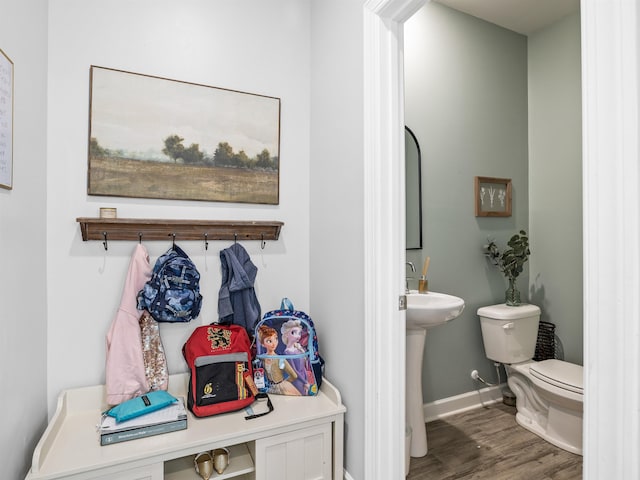 bathroom featuring toilet, a sink, baseboards, and wood finished floors