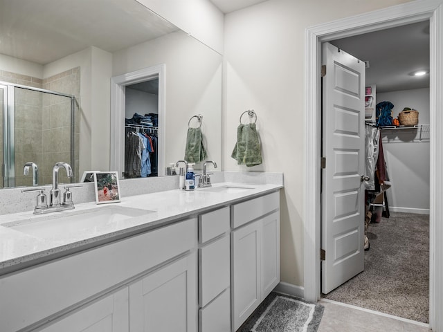 bathroom with a stall shower, a sink, a spacious closet, and double vanity