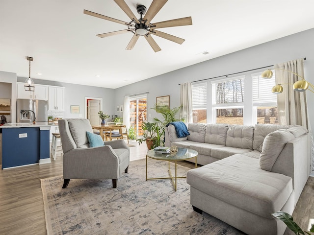 living area with visible vents, ceiling fan, and light wood-style flooring