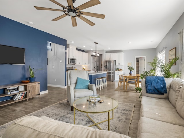 living area featuring ceiling fan, baseboards, wood finished floors, and recessed lighting