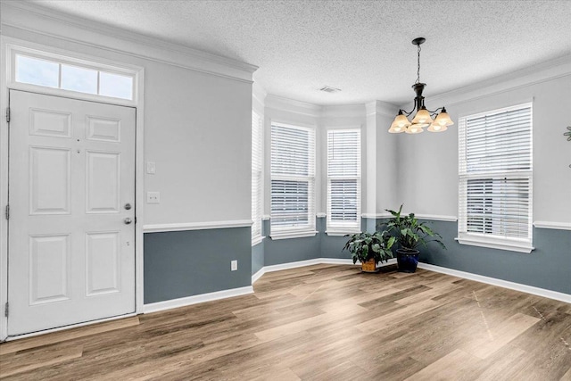 foyer featuring plenty of natural light, ornamental molding, and wood finished floors