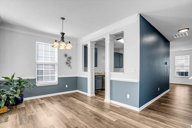 unfurnished dining area with an inviting chandelier, a textured ceiling, visible vents, and wood finished floors