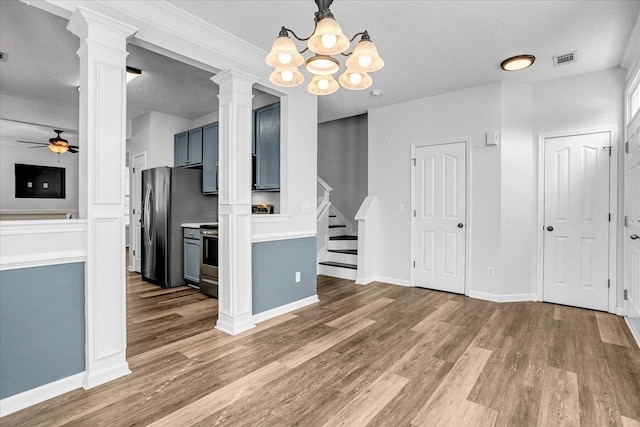 interior space featuring stairs, visible vents, wood finished floors, ornate columns, and ceiling fan with notable chandelier