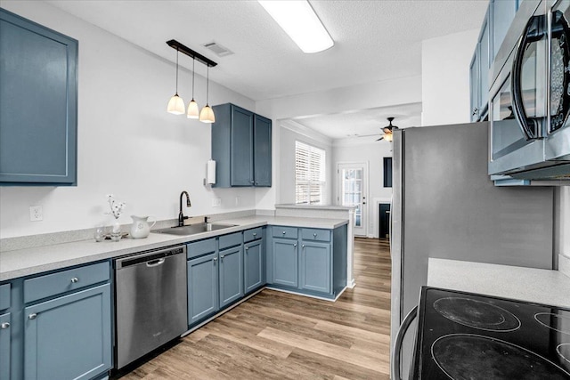 kitchen featuring a peninsula, blue cabinetry, appliances with stainless steel finishes, and a sink