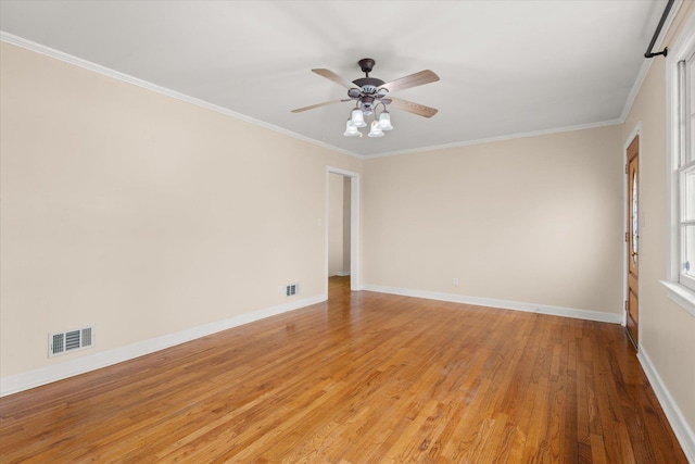 empty room with crown molding, visible vents, light wood-style floors, a ceiling fan, and baseboards