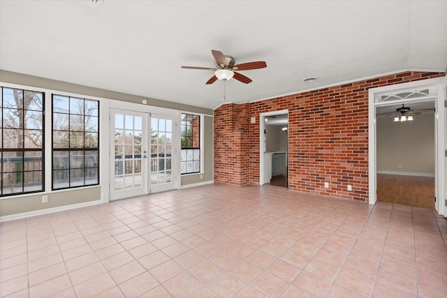 empty room with light tile patterned floors, brick wall, and a ceiling fan