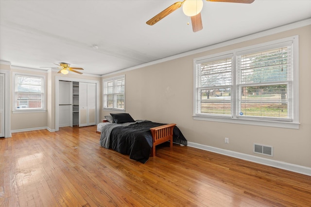 bedroom with light wood-style flooring, visible vents, and ornamental molding