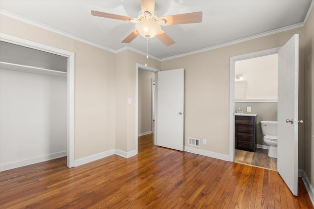 unfurnished bedroom with baseboards, visible vents, wood-type flooring, crown molding, and a closet