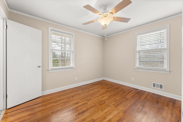 empty room featuring light wood-type flooring, baseboards, visible vents, and ornamental molding