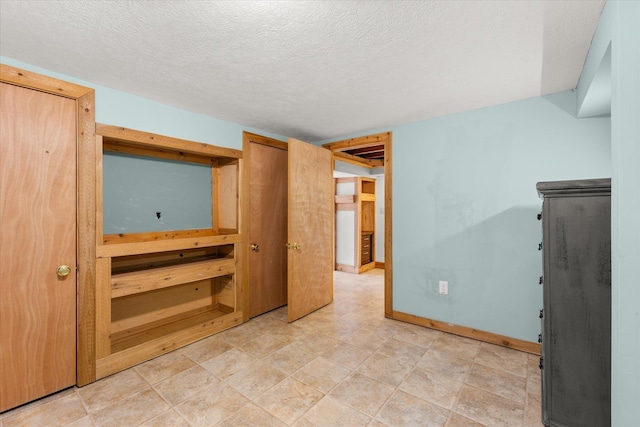 unfurnished bedroom featuring baseboards and a textured ceiling