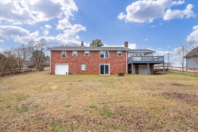 back of house with a garage, brick siding, a yard, and a wooden deck