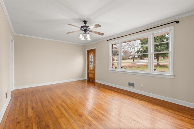 spare room featuring baseboards, ornamental molding, visible vents, and light wood-style floors