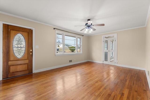 foyer with crown molding, visible vents, light wood-style floors, a ceiling fan, and baseboards