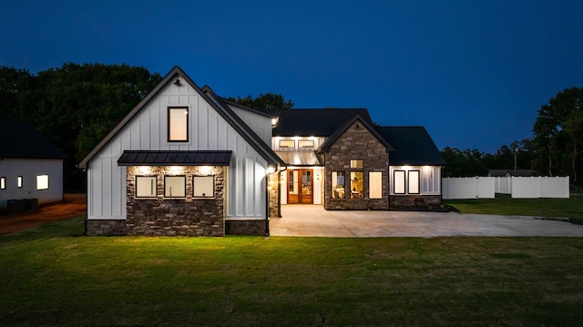 178 Cook, Chesnee, SC 29323 - back of house at night featuring board and batten siding, stone siding, a standing seam roof, and a patio