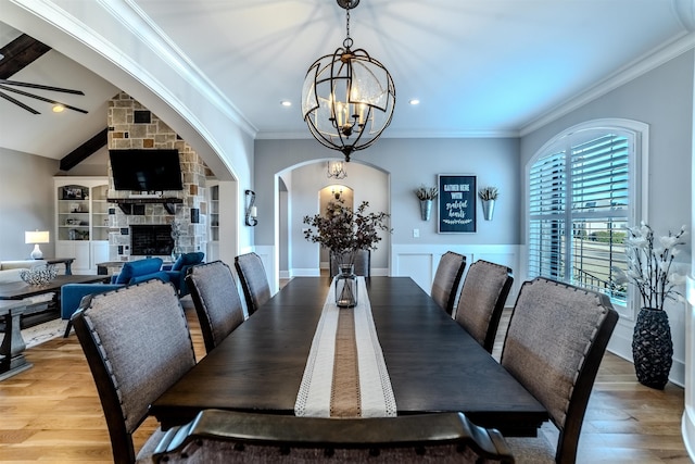 dining space with a chandelier, arched walkways, wood finished floors, and crown molding