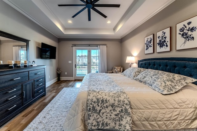 bedroom featuring dark wood-style flooring, baseboards, access to outside, a tray ceiling, and crown molding