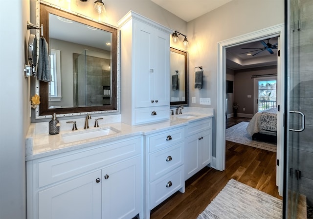 full bath featuring ensuite bathroom, double vanity, wood finished floors, and a sink