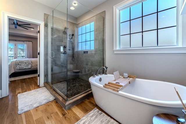 ensuite bathroom with a soaking tub, a shower stall, ensuite bath, and wood finished floors