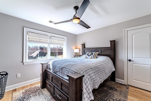 bedroom featuring ceiling fan, light wood finished floors, visible vents, and baseboards