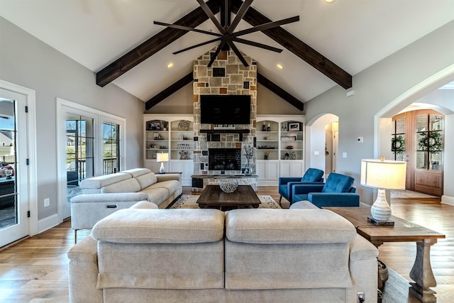 living area with beam ceiling, wood finished floors, a fireplace, and high vaulted ceiling