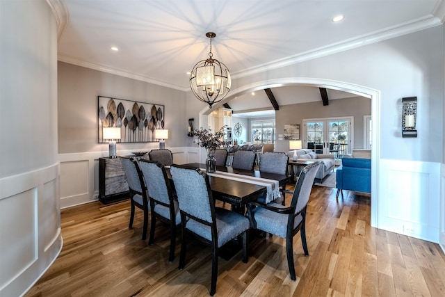 dining room featuring arched walkways, recessed lighting, a wainscoted wall, wood finished floors, and beamed ceiling