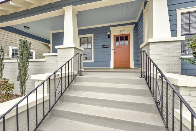 view of exterior entry featuring covered porch and brick siding