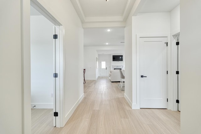 hall with light wood-style floors and baseboards