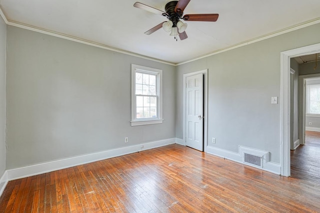 unfurnished room featuring attic access, a healthy amount of sunlight, ornamental molding, and hardwood / wood-style flooring