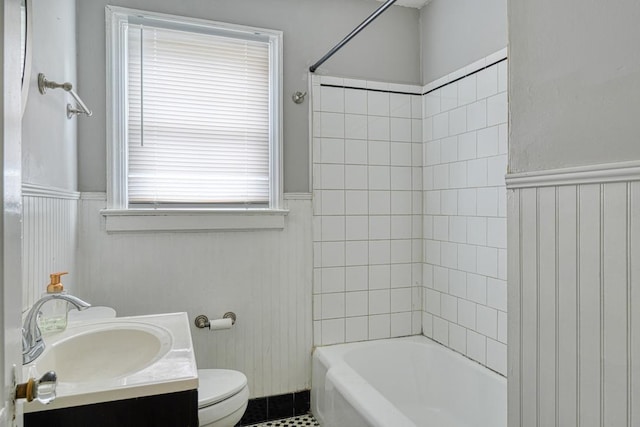 bathroom featuring toilet, a wainscoted wall, tub / shower combination, and vanity