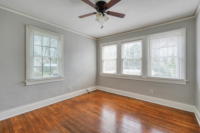 empty room with wood-type flooring, crown molding, and baseboards