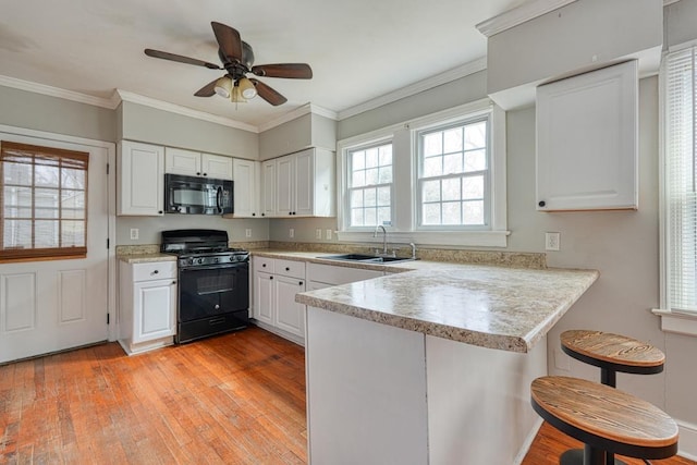 kitchen with crown molding, white cabinetry, a sink, a peninsula, and black appliances