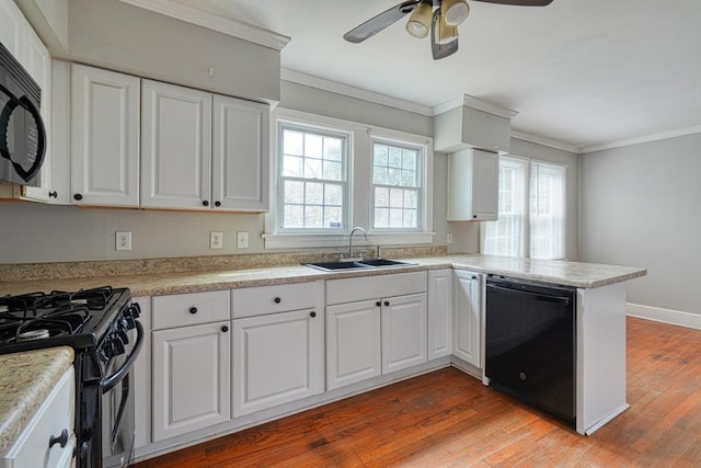 kitchen with a sink, white cabinets, light wood-type flooring, black appliances, and crown molding