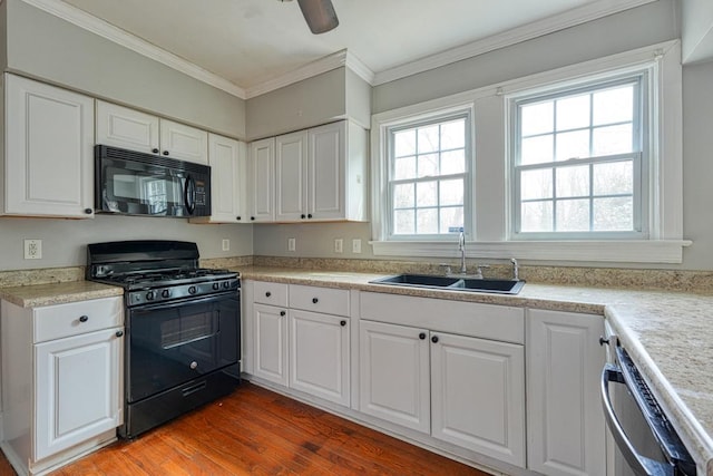 kitchen with wood finished floors, a sink, white cabinetry, ornamental molding, and black appliances