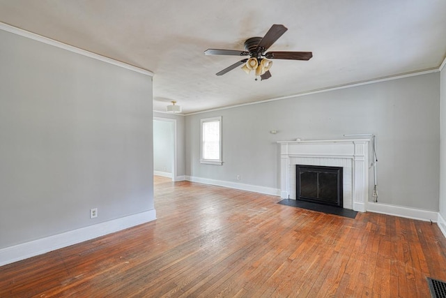 unfurnished living room featuring a brick fireplace, ornamental molding, and hardwood / wood-style floors