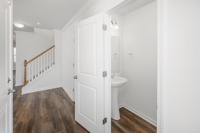 bathroom featuring a sink, baseboards, wood finished floors, and ornamental molding