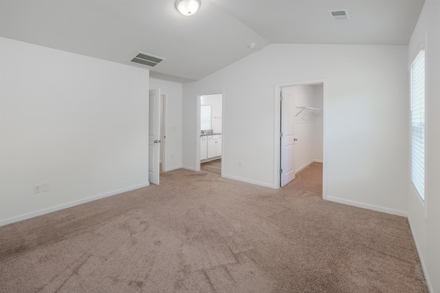 unfurnished bedroom with carpet, visible vents, and vaulted ceiling