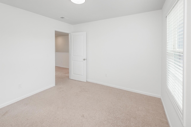 empty room with light carpet, plenty of natural light, visible vents, and baseboards