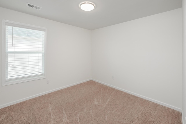 spare room with carpet floors, visible vents, and baseboards