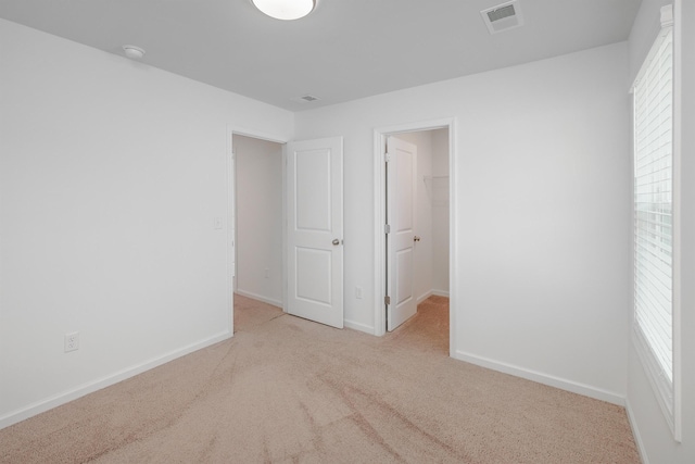 empty room featuring carpet floors, visible vents, and baseboards