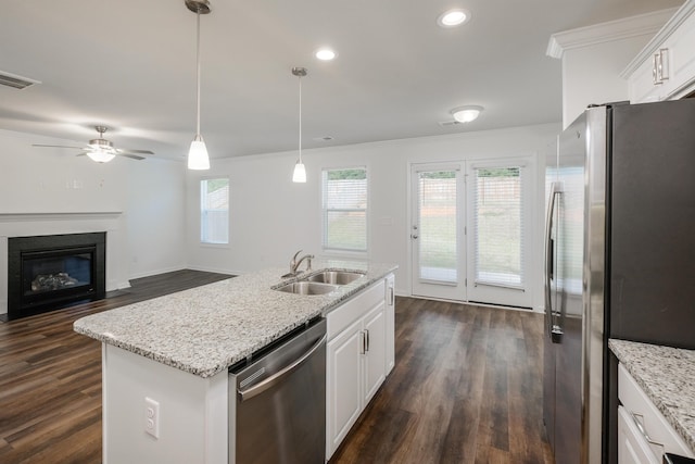 kitchen featuring stainless steel appliances, a sink, visible vents, white cabinetry, and a glass covered fireplace