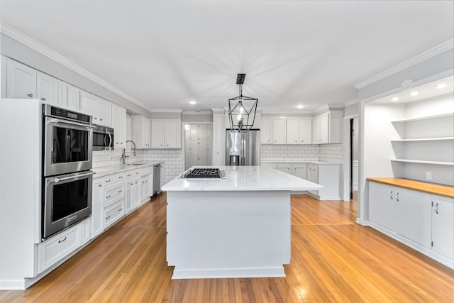 kitchen featuring white cabinets, a center island, stainless steel appliances, light wood-style floors, and a sink