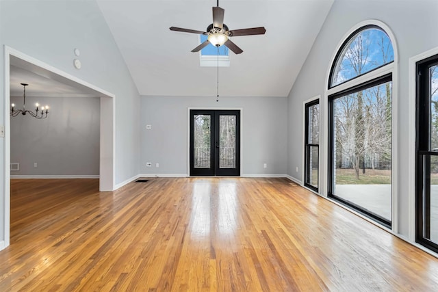 unfurnished room with high vaulted ceiling, ceiling fan with notable chandelier, baseboards, light wood-style floors, and french doors