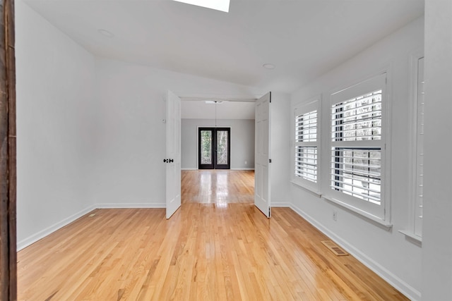 unfurnished room with french doors, visible vents, light wood-style flooring, and baseboards