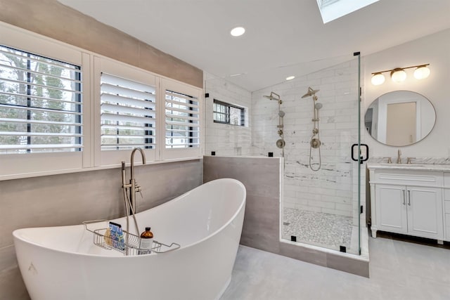 bathroom with tile walls, a soaking tub, a stall shower, vanity, and vaulted ceiling with skylight