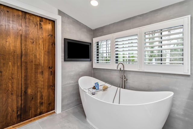 full bathroom featuring a freestanding bath, tile walls, and recessed lighting