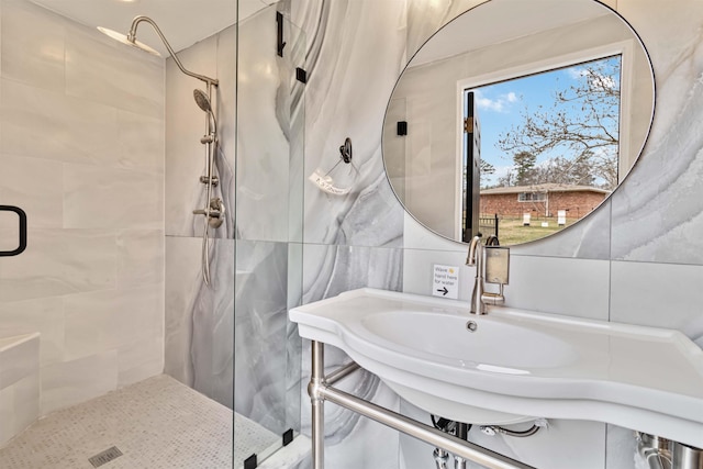 full bathroom with a sink, backsplash, a shower stall, and tile walls