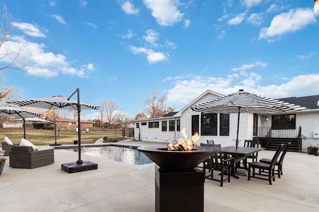 view of pool with a fire pit, outdoor dining area, a fenced in pool, and a patio