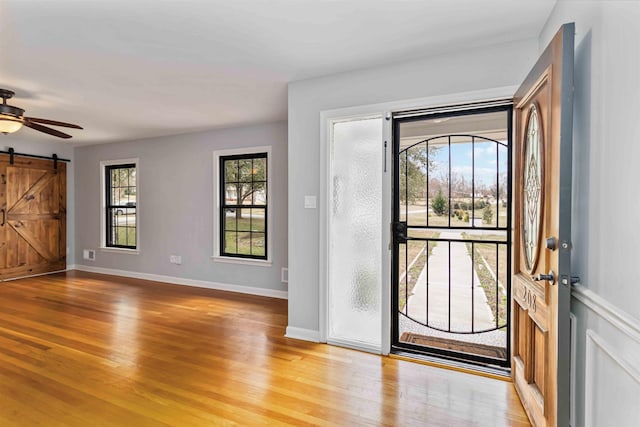 entryway featuring light wood-type flooring, a barn door, baseboards, and a ceiling fan