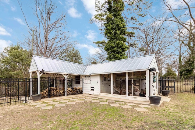 back of property featuring a lawn, metal roof, exterior structure, fence, and an outdoor structure